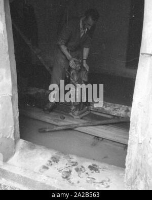 The flood in Passau and other parts of Lower Bavaria (July, 1954) were also referred to as the flood of the century. The Danube, the Inn and the Ilz had overflowed their banks, and flooded towns and villages. Photo of a helper bringing out a statue from a church flooded with water and soil. Stock Photo