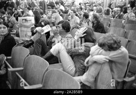 Members of the Ausserparlamentarische Opposition (extra-parliamentary opposition APO) gained access to an election campaign of the CSU with forged tickets in the Bayernhalle in Munich. Photo of members of the APO covering their faces in the audience at a CSU event. Stock Photo