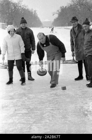 Dan Blocker, who plays the role of Hoss Cartwright in the television series Bonanzna, here in the center, with an ice stock in his hand while curling on the Nymphenburg Canal. Around him are some players. Stock Photo