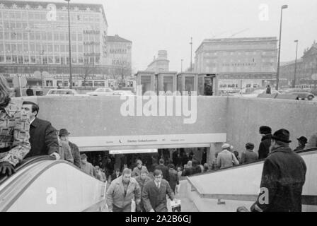 Entrance and exit from the lower level at Stachus, which leads to the S-Bahn and the Stachus shopping center. In the background at left, the department store 'Kaufhof' with advertisements of 'Zechbauer Zigarren' in the middle the Hotel Koenigshof (Der Koenigshof) and at left, cut, the Palace of Justice. Stock Photo