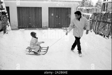 Roberto Blanco plays in the snow with his daughter Mercedes and a sled in 1970. Stock Photo