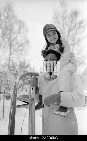 Roberto Blanco plays in the snow with his daughter Mercedes and a sled in 1970. Stock Photo