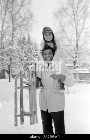 Roberto Blanco plays in the snow with his daughter Mercedes and a sled in 1970. Stock Photo