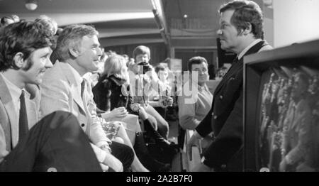 Wim Thoelke turns to Joachim Fuchsberger, who sits in the audience at his television show 3x9 . Right in the foreground is a TV screen. Stock Photo