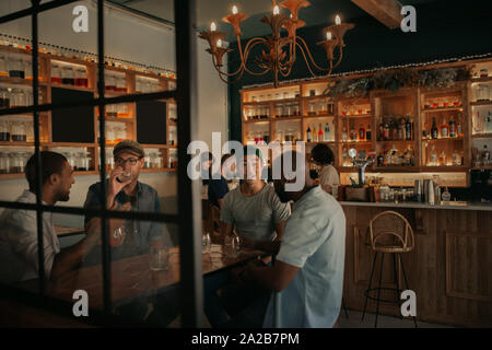 Diverse group of guys talking over drinks in a bar Stock Photo