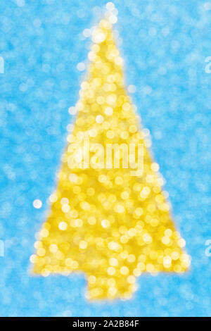 Abstract blurred bokeh photo of golden Christmas tree shape made of glitter on sparkly blue paper, selective focus Stock Photo