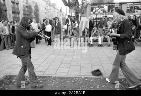 Street musician in the Schwabing district in Munich. The performance takes place in front of the shopping and entertainment complex 'Citta 2000' in the Leopoldstrasse. Stock Photo