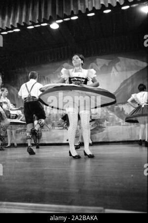 A dancer in traditional costume with flying skirt during a performance of traditional Bavarian folk dances in a spa town in Bavaria. Stock Photo