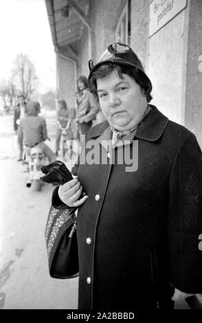 Mrs. Baumann, who distributed the publication of the Süddeutsche Zeitung 'Das vergiftete Gehirn' ('The poisoned brain') in a campaign against narcotics in Munich. In the background, teenagers on motor scooters. Stock Photo