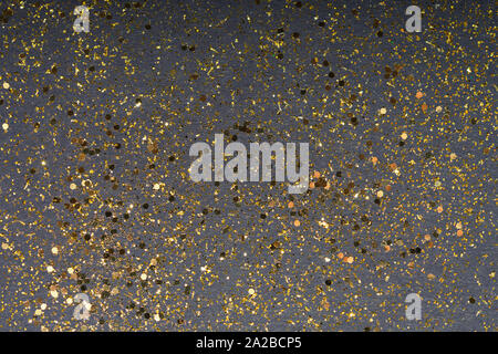 Golden glitter and scattered on the dark card background, top view, selective focus Stock Photo