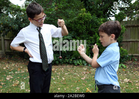 Two school children in school uniform playing conkers having a conker fight outside in Autumn 2019 Stock Photo