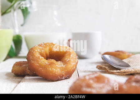 Spanish roscos or donuts at breakfast on a white wooden table next to a cup of coffee and a jar of milk. White background and empty copy space Stock Photo