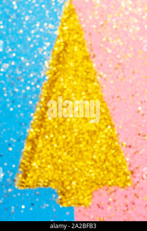 Holiday concept, golden glitter scattered on blue and pink card in a shape of Christmas tree, top view. Abstract composition, blurred photo with bokeh Stock Photo