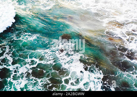 waves crashing over rocks shot from the air