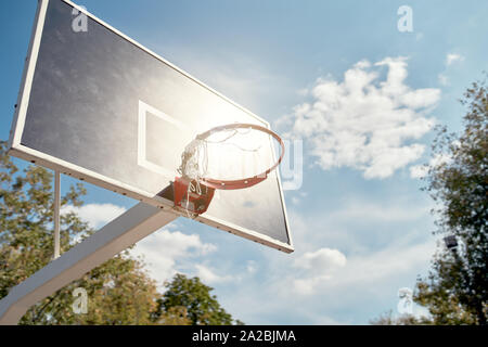 Image of basketball hoop against blue, cloudy sky on summer day. Sunflare effect. Stock Photo