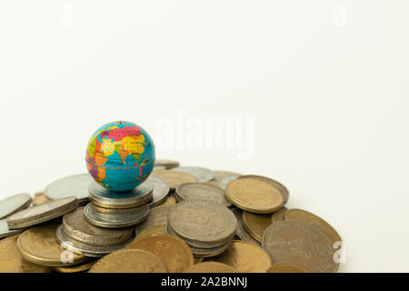 Concept of whole world stand on Money, Stack of Indian currency coins with globe above the coins on isolated background. Stock Photo