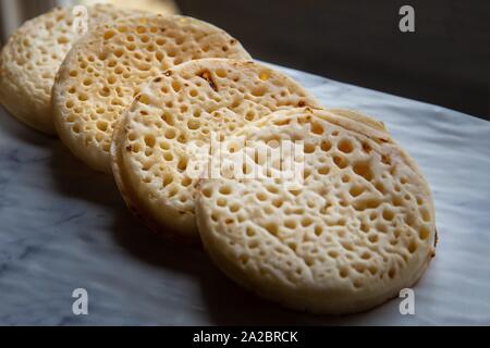 Hot toasted English crumpets arranged in a line.