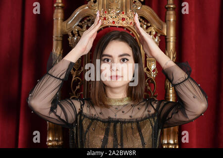 Close up portrait of a queen putting on crown Stock Photo