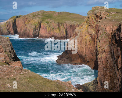 Sea cliffs near North Ham on Muckle Roe, Shetland, UK - the rock is of the Muckle Roe Intrusion - granite, granophyric - igneous bedrock. Stock Photo