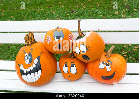 Many pumpinks with painted faces on white porch. Stock Photo