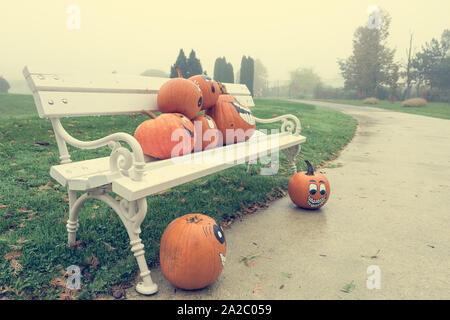 Many pumpinks with painted faces on white porch. Stock Photo