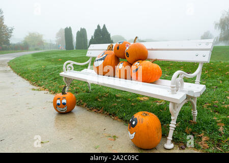 Many pumpinks with painted faces on white porch. Stock Photo