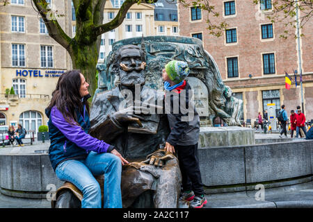 A woman and a boy sitting on  the Bronze statue of Charles Buls or Karel Buls, a famous mayor of the City of Brussels during 1881-1899, at Grass Marke Stock Photo