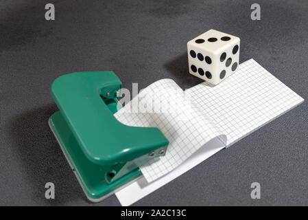 White dice.Note paper, hole punch and opposite organizer. Business and work concept. Stationery notebook with blank pages. Office tools on grey backgr Stock Photo