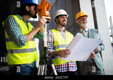 Confident team of architects and engineers working together on construction site Stock Photo