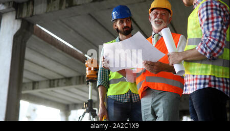 Male architects analyzing blueprint at construction site Stock Photo