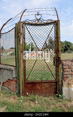 Old rusty metal door next to a ruined brick wall Stock Photo