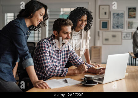 Smiling group of designers working together on an office laptop Stock Photo