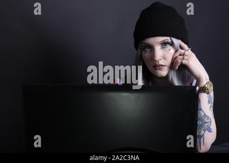 Millennial woman looking at camera over laptop, low key 2019 with copy space Stock Photo