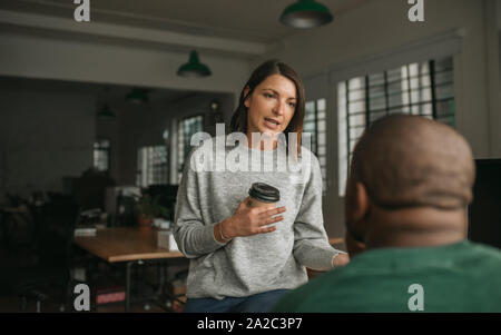 Female designer talking with a colleague in an office Stock Photo