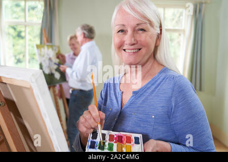 Portrait Of Senior Woman Attending Painting Class With Teacher          In Background Stock Photo