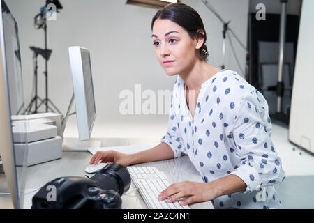 Female Photographer In Studio Reviewing Images From Photo Shoot On Computer Stock Photo