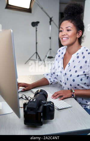 Female Photographer In Studio Reviewing Images From Photo Shoot On Computer Stock Photo