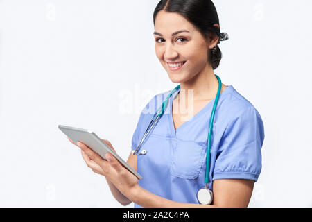 Portrait Of Studio Shot Of Female Nurse Wearing Scrubs Using Digital Tablet Stock Photo