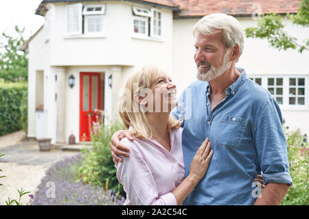 Mature Couple Standing In Garden In Front Of Dream Home In Countryside Stock Photo