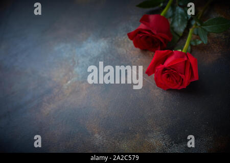 Red roses lie on a textured spotted marble background. A sign of condolence, sympathy for the loss. Stock Photo