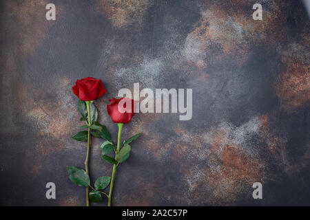 Red roses lie on a textured spotted marble background. A sign of condolence, sympathy for the loss. Stock Photo