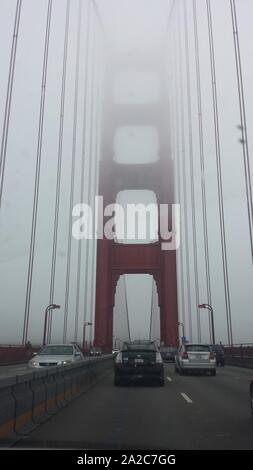 Car point of view traveling over the Golden Gate Bridge, with spires of the bridge ascending into fog, San Francisco, California, June 20, 2015. () Stock Photo