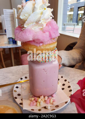 Pink strawberry freakshake with sweets, donuts and wipped cream in cafe, extreme milkshake Stock Photo