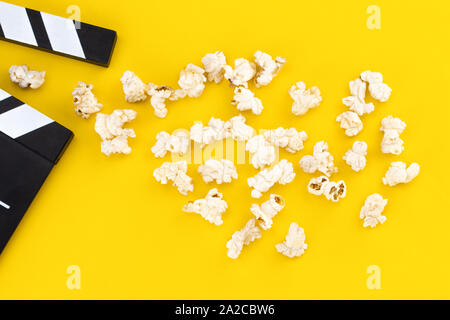 Popcorn and clapperboard on colorful background. Top view. Stock Photo