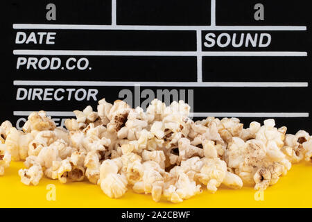 Popcorn and clapperboard on colorful background. Stock Photo