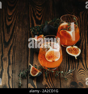 Pink cocktail with fig, thyme and ice in glass on dark wooden background, close up. Summer drinks and alcoholic cocktails. Alcoholic or detox cocktail Stock Photo