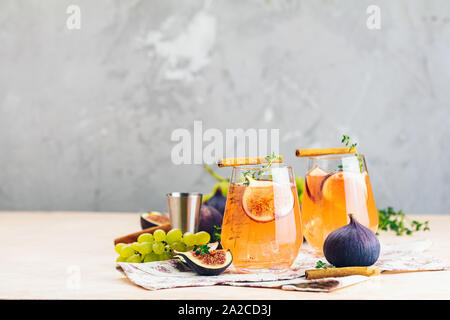Pink cocktail with fig, thyme, cinnamon and grapes in glass on pink concrete background, close up. Autumn drinks and alcoholic cocktails. Alcoholic co Stock Photo