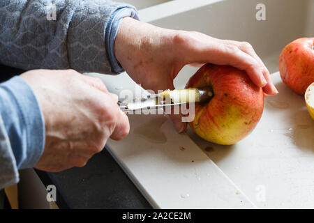 Hands of a woman removing an apple core with an apple corer in a kitchen Stock Photo