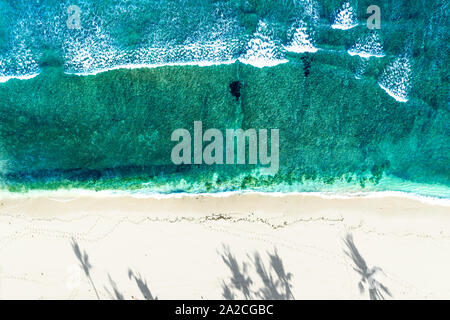 Aerial view looking down onto a tranquil cove with large waves breaking onto the beach Stock Photo