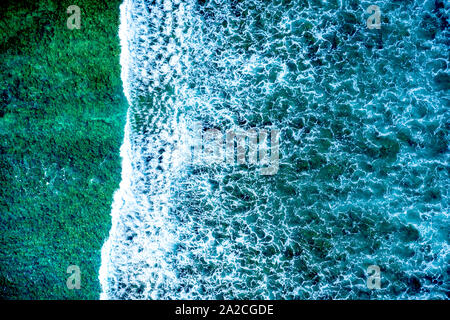 Aerial view looking straight down onto large waves in a tropical ocean